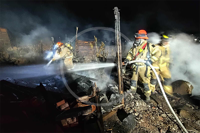 Bomberos de Morelia trabajando entre escombros de casas de madera tras un incendio.