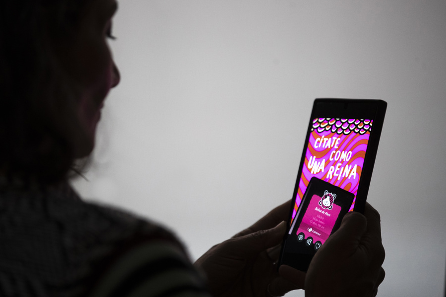 Una persona usando una aplicación de citas en su celular con iconos de corazones.