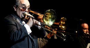 Willie Colón tocando el trombón durante un concierto icónico de salsa.