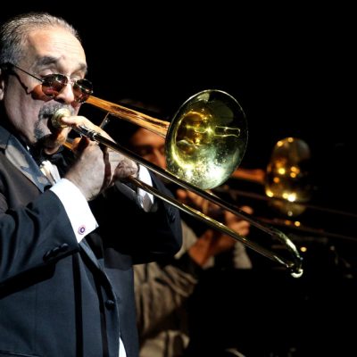 Willie Colón tocando el trombón durante un concierto icónico de salsa.