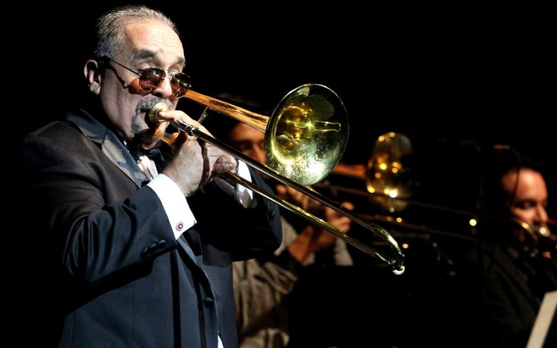 Willie Colón tocando el trombón durante un concierto icónico de salsa.