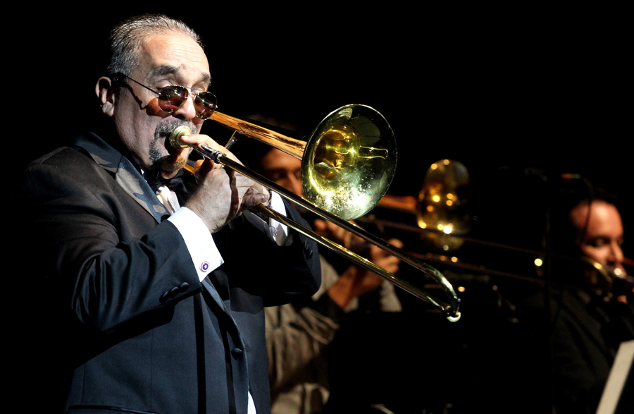 Willie Colón tocando el trombón durante un concierto icónico de salsa.