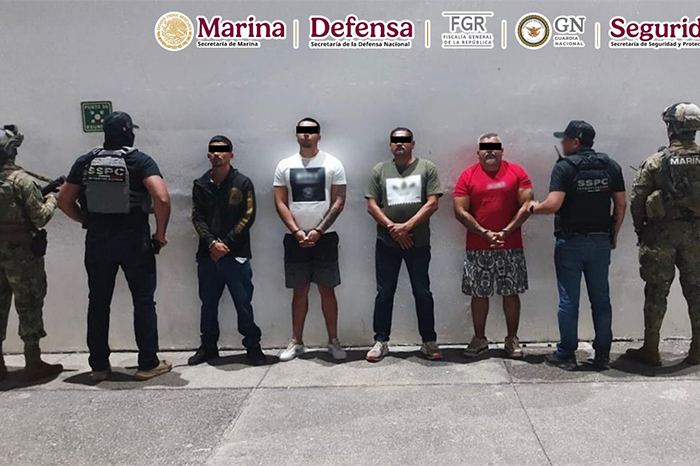 Elementos de las fuerzas de seguridad custodiando a detenidos tras operativo en Puerto Vallarta.