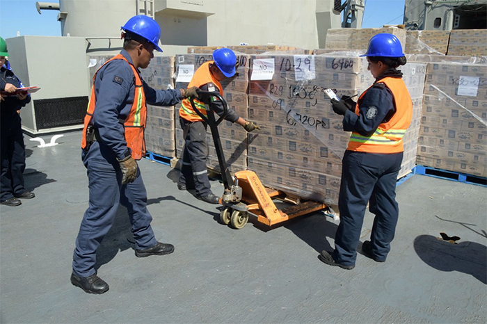 Cajas de víveres y leche en polvo siendo cargadas en buques de la Armada de México en Veracruz.