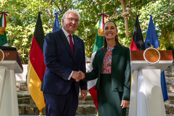 La presidenta de México, Claudia Sheinbaum, y el presidente de Alemania, Frank-Walter Steinmeier, se dan la mano frente a las banderas de ambas naciones en Cancún.