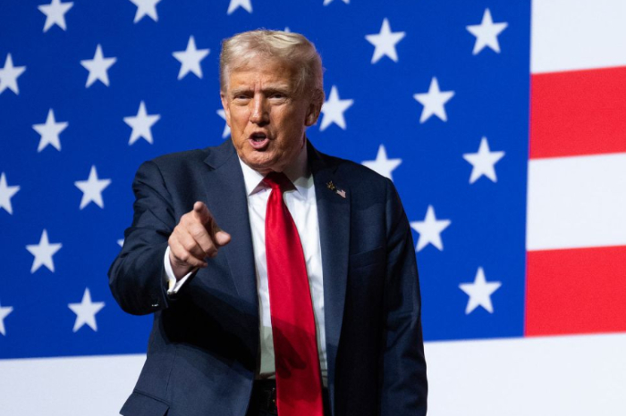 El presidente Donald Trump gesticulando durante una rueda de prensa en la Casa Blanca frente a la bandera de Estados Unidos.