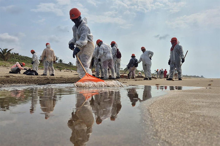 Brigadas de limpieza recolectando residuos de chapopote en una playa de Veracruz tras derrame en el Golfo de México.