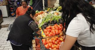 Cliente comparando precios de frutas y verduras como limón y jitomate en un mercado local tras el reporte de inflación del Inegi.