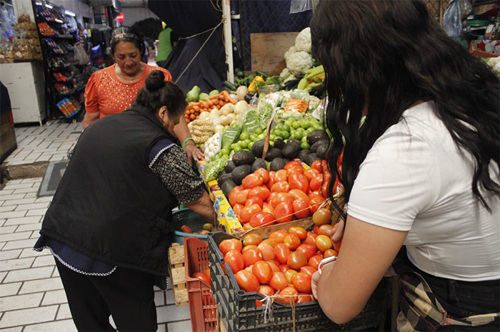 Cliente comparando precios de frutas y verduras como limón y jitomate en un mercado local tras el reporte de inflación del Inegi.