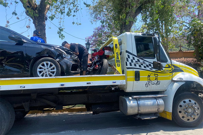 Elementos de Tránsito y Vialidad atendiendo un choque entre una motocicleta roja y un auto negro en Avenida Camelinas.