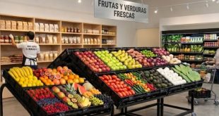 Exhibidor de frutas y verduras organizado por contraste de color y categorías en un minisuper moderno.
