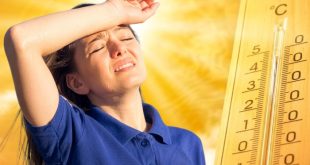 Mujer joven sufriendo por el intenso calor junto a un termómetro que marca temperaturas altas bajo el sol.