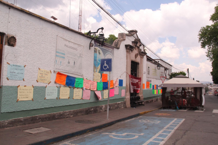 Fachada de las oficinas de la Secretaría de Salud de Michoacán con pancartas de manifestantes