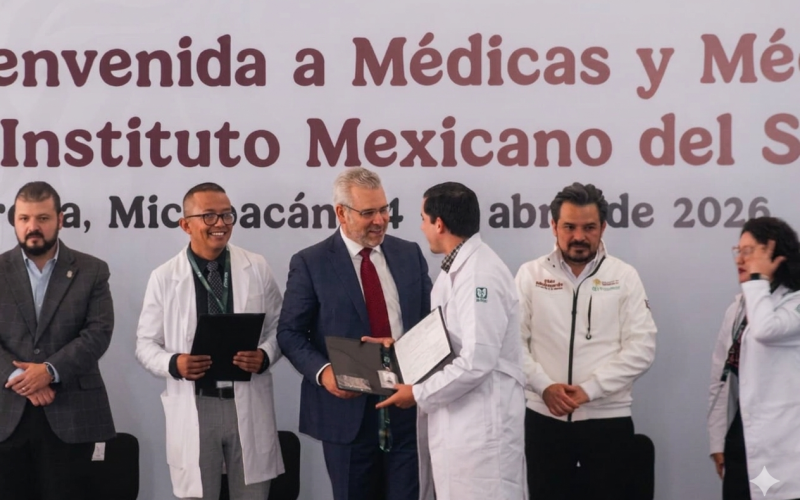 El gobernador Alfredo Ramírez Bedolla entrega documentos a un médico especialista durante el evento de bienvenida al IMSS en Michoacán.