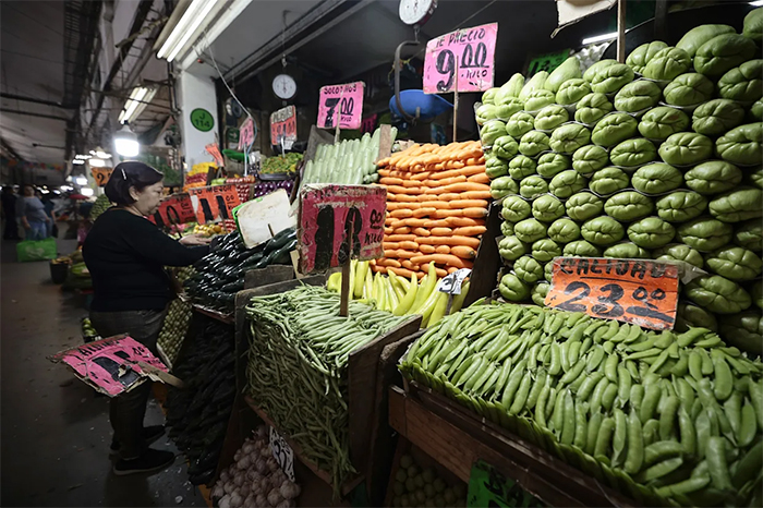 Consumidores en un mercado de abastos revisando precios de productos básicos como el jitomate y chiles tras el reporte de inflación del Inegi.