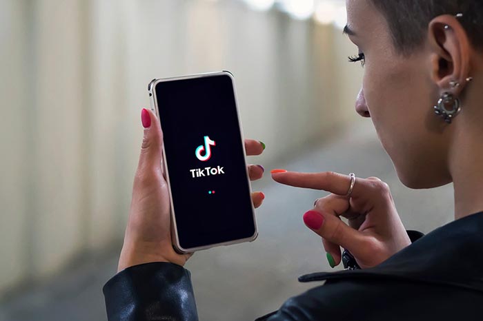 Un joven utilizando la barra de búsqueda de TikTok en su teléfono móvil para encontrar información.