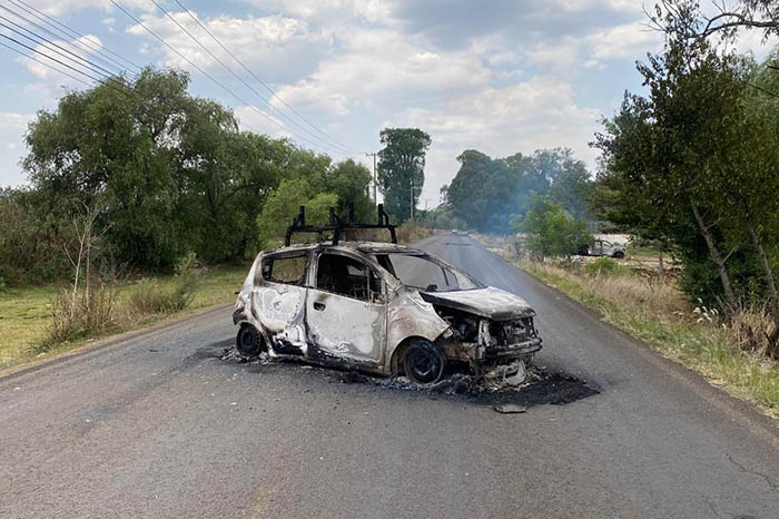 Vehículos incendiados sobre la carretera en Tiripetío, Morelia, durante protesta de normalistas.