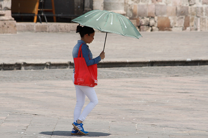 Ciudadanos en el centro de Morelia protegiéndose del sol con sombrillas y gorras ante las altas temperaturas.