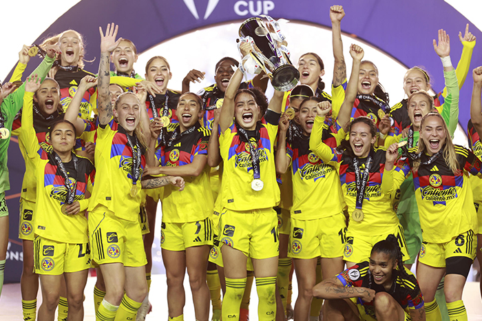 Jugadoras del Club América Femenil festejando con el trofeo de la Concacaf W en el podio del Estadio Hidalgo.