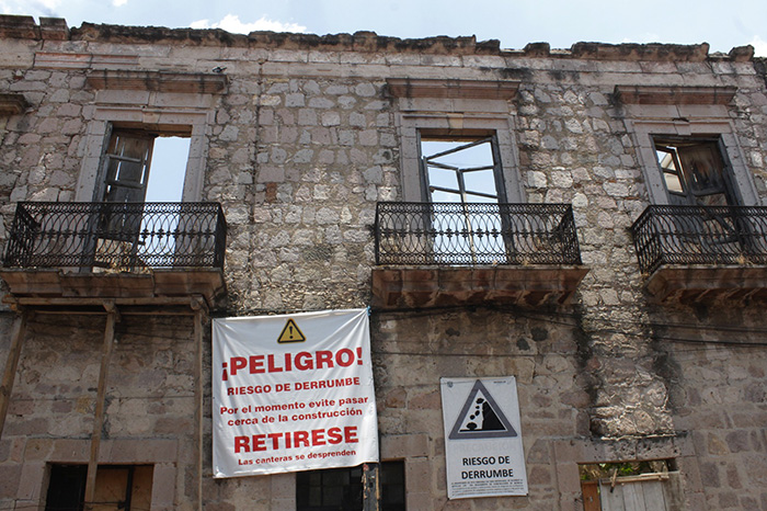 Fachada antigua de cantera en el Centro Histórico de Morelia apuntalada con tapiales y mallas de protección por riesgo de colapso.