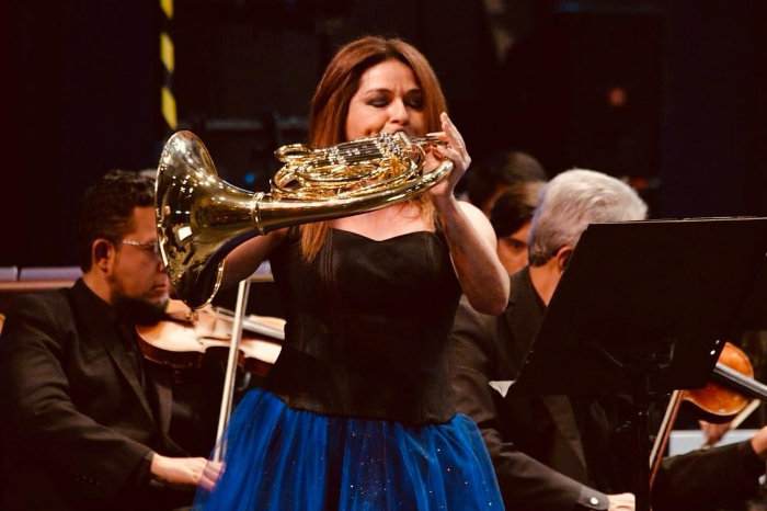 Jenny Cardenas cornista venezolana mexicana sonriendo con su instrumento corno frances