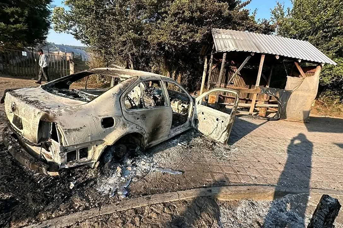 Restos de un vehículo incendiado y casetas de madera siniestradas en el acceso a Agua Verde, Zirahuén.