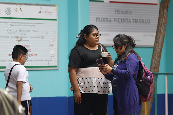 Madres y padres de familia conversando afuera de una escuela secundaria en la Ciudad de México.