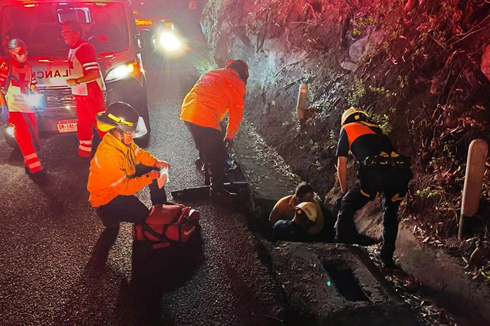 Bomberos de Protección Civil Michoacán realizan maniobras de rescate de un peatón en un registro pluvial.