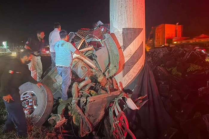 Rescatistas y bomberos municipales trabajando con equipo hidráulico junto a un camión torton siniestrado en la cuneta central de la carretera.