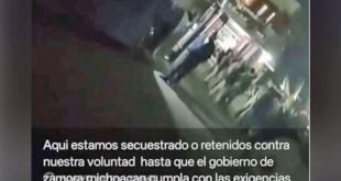 Tractocamiones de carga estacionados a la orilla de una carretera rural bajo resguardo de manifestantes.