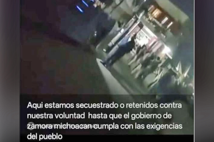Tractocamiones de carga estacionados a la orilla de una carretera rural bajo resguardo de manifestantes.