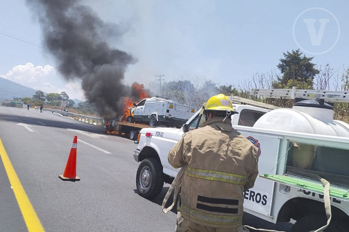 Grúa de plataforma y camioneta de servicio envueltas en llamas y humo negro sobre el kilómetro 87 de la autopista Siglo XXI.