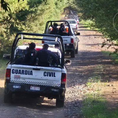 Elementos de la Guardia Civil resguardando camionetas aseguradas en un camino de terracería rural.