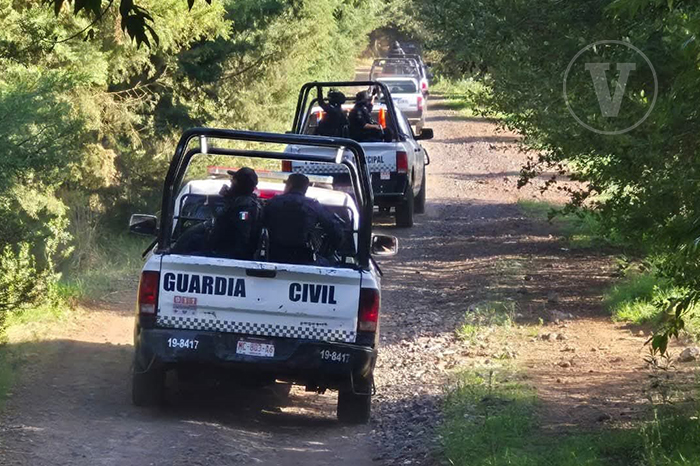 Elementos de la Guardia Civil resguardando camionetas aseguradas en un camino de terracería rural.