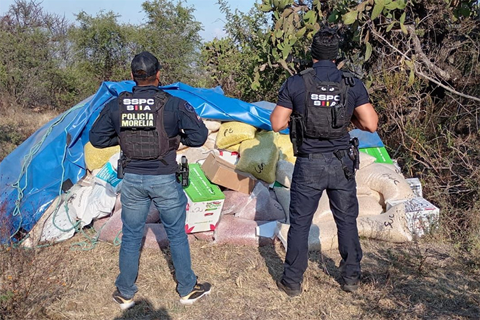 Agentes de la Policía Morelia resguardando costales de granos y abarrotes recuperados en una brecha de la salida a Mil Cumbres.
