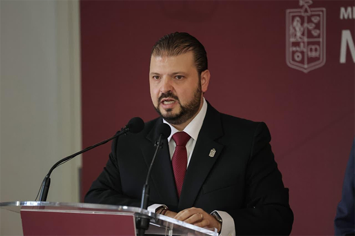 El secretario de Gobierno de Michoacán, Raúl Zepeda Villaseñor, hablando detrás de un podio oficial durante una conferencia de prensa sobre la reforma electoral.
