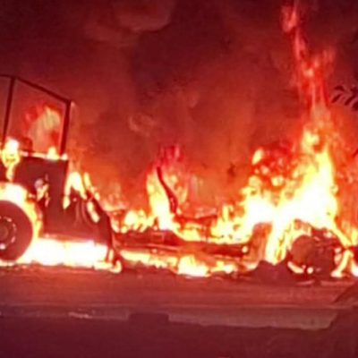 Restos de un autobús de pasajeros incendiado sobre la carpeta asfáltica de la carretera costera en Michoacán.