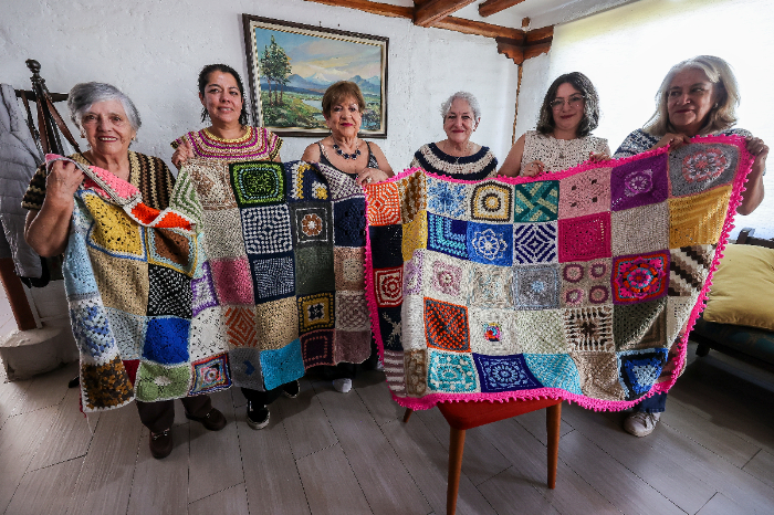 Grupo de mujeres de la familia Chauvin tejiendo cuadrados de lana coloridos en Ecuador.