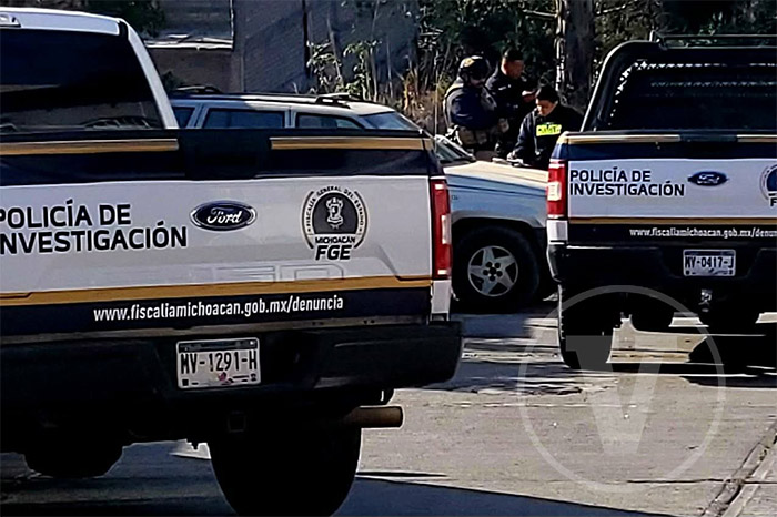 Elementos de la Fiscalía realizan el levantamiento de un cuerpo en un terreno baldío.