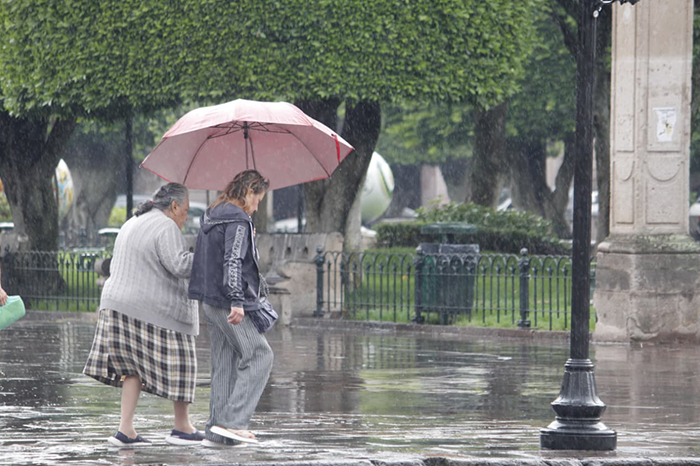Personas caminando bajo la lluvia en el centro de Morelia