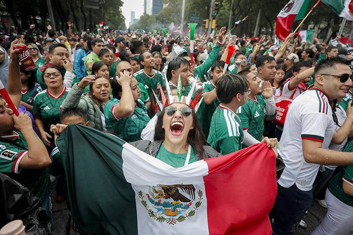 Aficionados celebrando la victoria de la selección mexicana mientras se observan movilizaciones sociales en Ciudad de México.