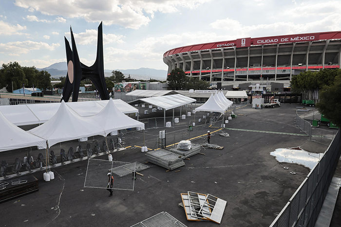 Vecinos caminando cerca del Estadio Ciudad de México ante las vallas de seguridad y filtros implementados para el Mundial.
