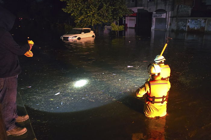 Personal operativo de rescate de Michoacán caminando sobre una calle inundada con agua a nivel de las llantas de los automóviles.