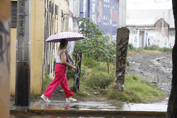 Mujer caminando bajo la lluvia con un paraguas en Morelia.