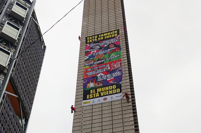 Activistas de Greenpeace despliegan una manta gigante en la Estela de Luz contra el gasto en el Mundial de Fútbol 2026.