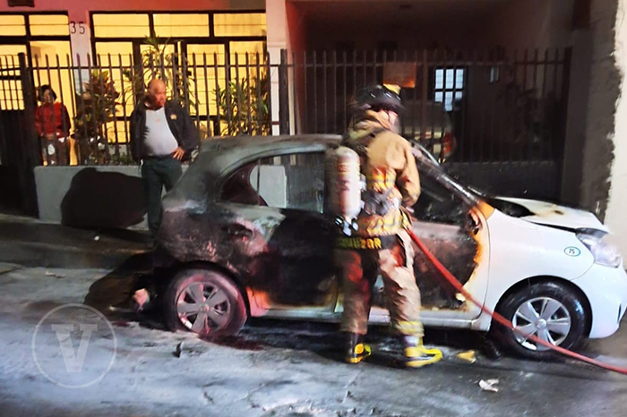 Elementos de bomberos controlando el incendio de un taxi en el Barrio Mágico de San Pedro, Uruapan.