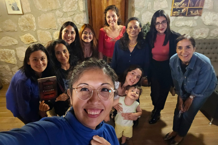 Grupo de mujeres reunidas en una mesa con libros abiertos y tazas de café