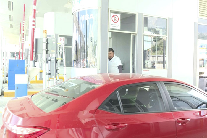 Vehículos cruzando por carriles con sistema de telepeaje en una caseta de cobro federal.