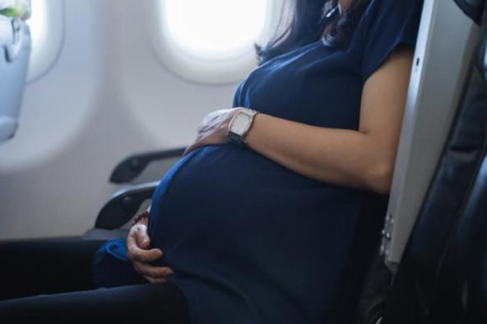 Mujer embarazada en un avión, a punto de viajar.