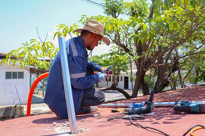 Personal municipal realizando labores de revisión y cambio de cableado eléctrico en una institución educativa.